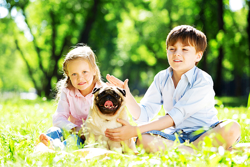 Adorable boy and girl in summer park with their dog