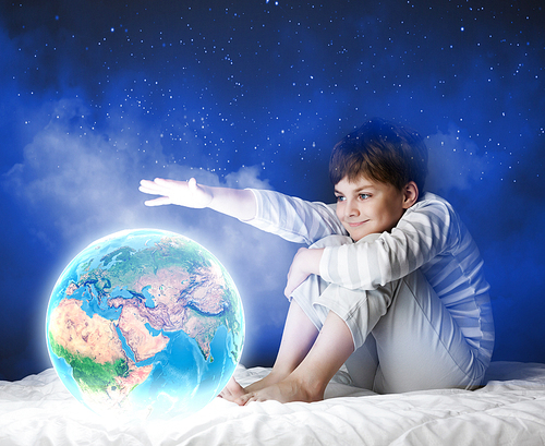 Cute boy sitting in bed and looking at Earth planet. Elements of this image are furnished by NASA