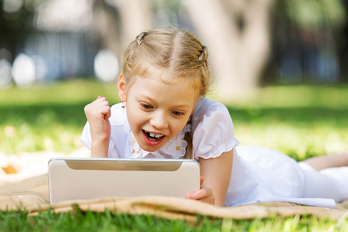 Little cute girl in summer park reading book