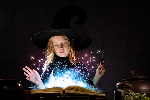 Little Halloween witch reading conjure from magic book