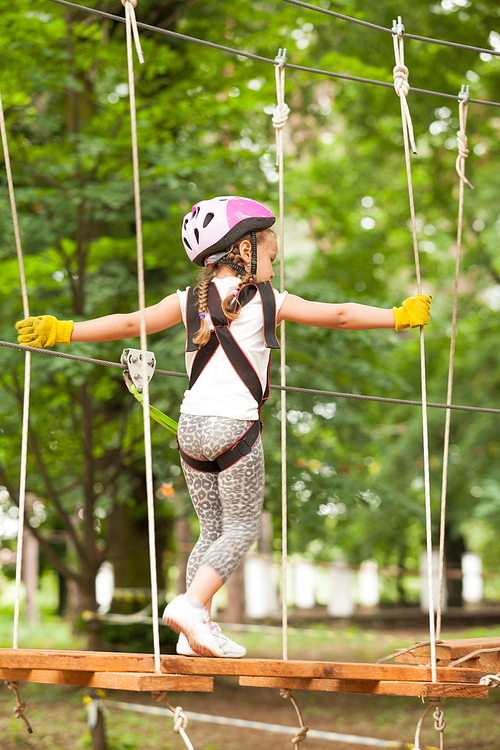 Kids on obstacle course in adventure park in mountain helmet and safety equipment