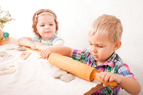 Little boy using a rolling pin that to roll modelling clay