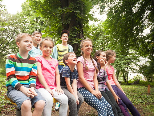 Group of positive children playing in the park sitting on the bench