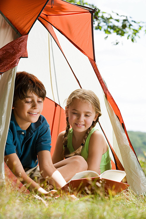 Boy and girl reading in a tent