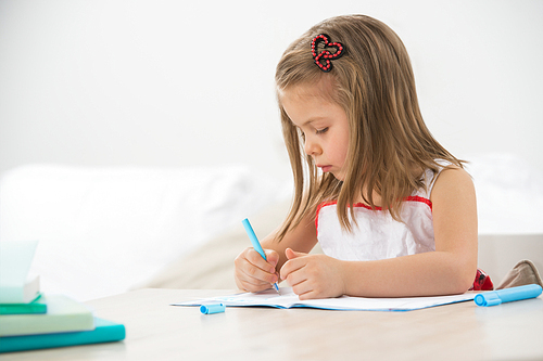 Happy little girl drawing with pencils at home