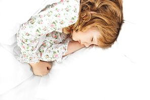 Closeup portrait of adorable little girl resting in her bed with white linen