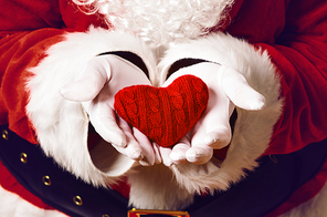 Santa Claus holding red knitted heart in both hands