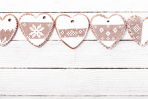 Gingerbread cookies in shape of heart with icing on a wooden background