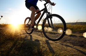 Male cyclist driving by rural dirt road outdoors. Low angle view