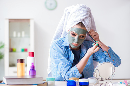 Woman applying clay mask with brush at home