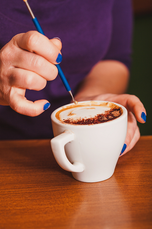 Barista is show how to make latte art coffee. Lesson with special metal device - latte-art pen tool.