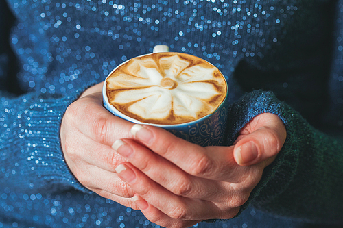 Woman holding a cup of coffee latte with beautiful pattern