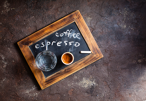 Top view of a cup of coffee and glass water on an old school slate with inscription