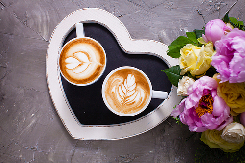 Latte art in two cups of cappuccino on the heart shape tray. Happy morning Valentine day couple