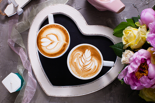 Latte art in two cups of cappuccino on the heart shape tray. Happy morning Valentine day couple