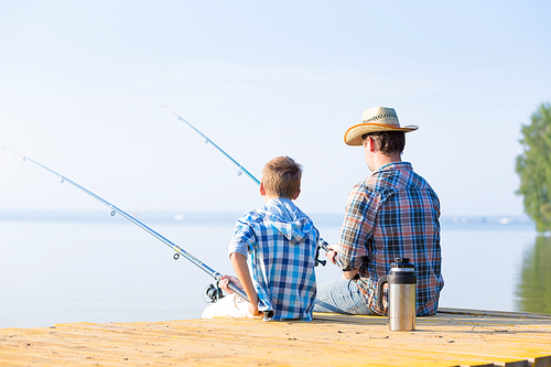 boy and his father fishing together from a pier