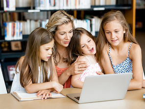 Little girls and their mum with a laptop in library
