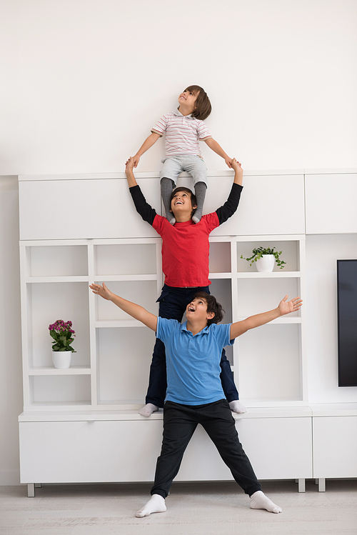 happy young boys having fun and posing line up piggyback in new modern home