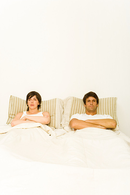Couple in bed ignoring each other
