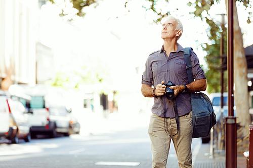 Senior man with camera in city