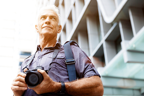 Senior man with camera in city