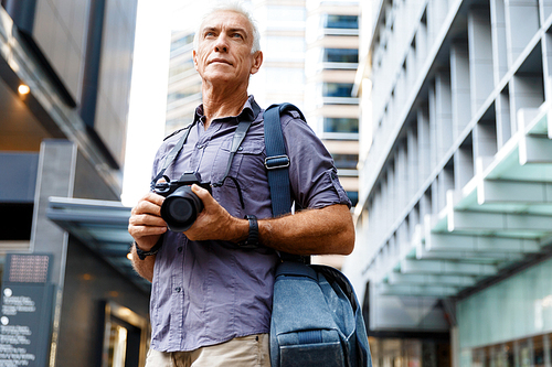 Senior man with camera in city