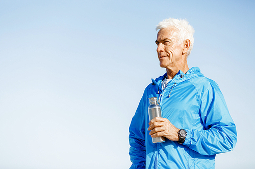 Confident man in sport wear holding bottle with water
