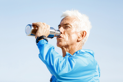 Handsome healthy man in sport wear drinking from sports bottle