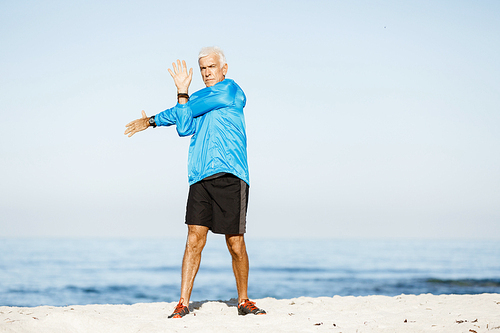 Handsome caucasian male doing exercises on beach