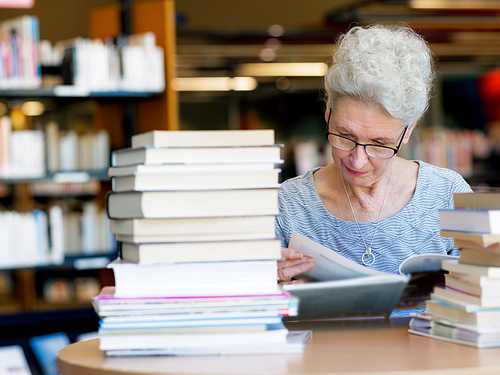 Elderly lady reading books in library