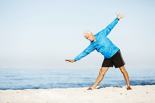 Handsome caucasian male doing exercises on beach