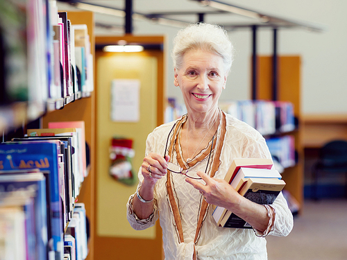 Elderly lady standing next to book shelves in library
