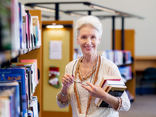 Elderly lady standing next to book shelves in library