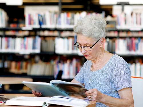 Elderly lady reading books in library