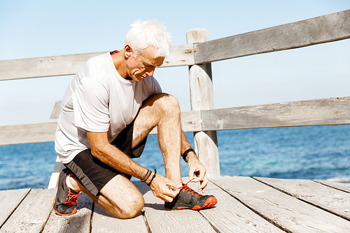 Male runner laces his shoes and prepares to jogging