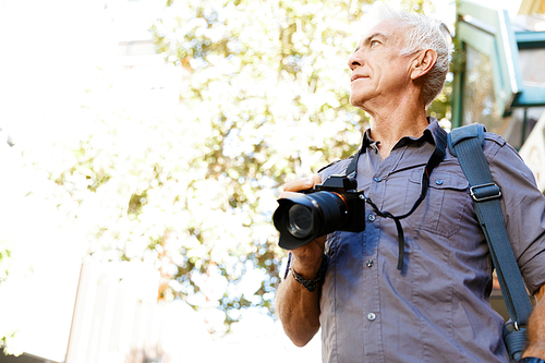 Senior man with camera in city