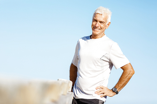 Man standing on beach in sports wear looking fit and happy