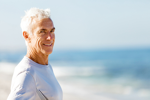 Man standing on beach in sports wear looking fit and happy