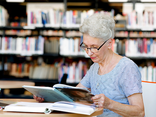 Elderly lady reading books in library