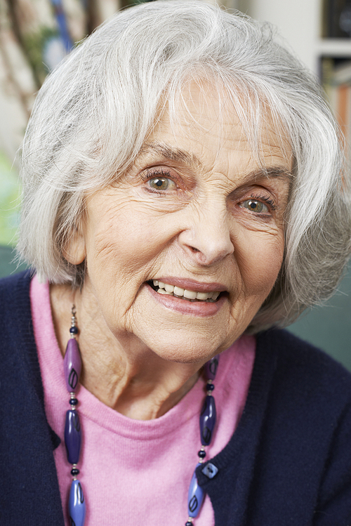 Head And Shoulders Portrait Of Smiling Senior Woman At Home