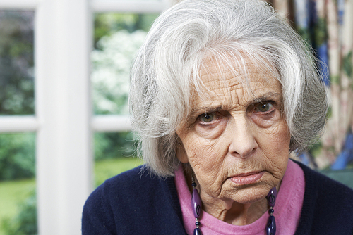 Head And Shoulders Portrait Of Angry Senior Woman At Home