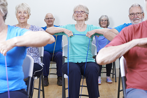 Group Of Seniors Using Resistance Bands In Fitness Class