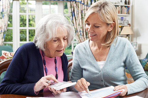 Female Neighbor Helping Senior Woman With Domestic Finances