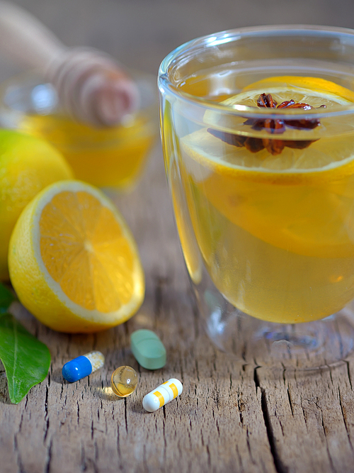 Hot lemon tea and pills on wooden table