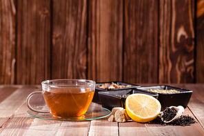 Black tea with lemon and brown sugar cubes on the wooden table, place for text