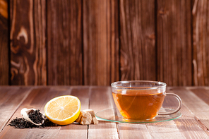 Black tea with lemon and brown sugar cubes on the wooden table, place for text