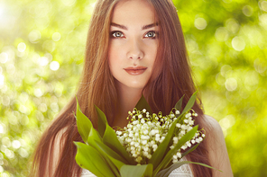 Portrait of beautiful young woman with lily of the valley. Girl on nature. Spring flowers. Fashion beauty