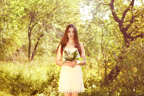 Portrait of beautiful young woman with lily of the valley. Girl on nature. Spring flowers. Fashion beauty