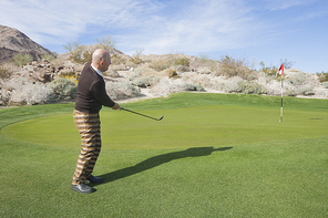 Full length side view of senior male golfer swinging his club at golf course