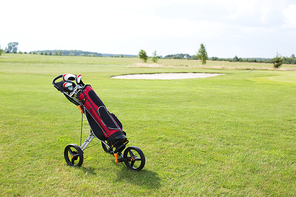 Golf club bag on pushcart at golf course against sky